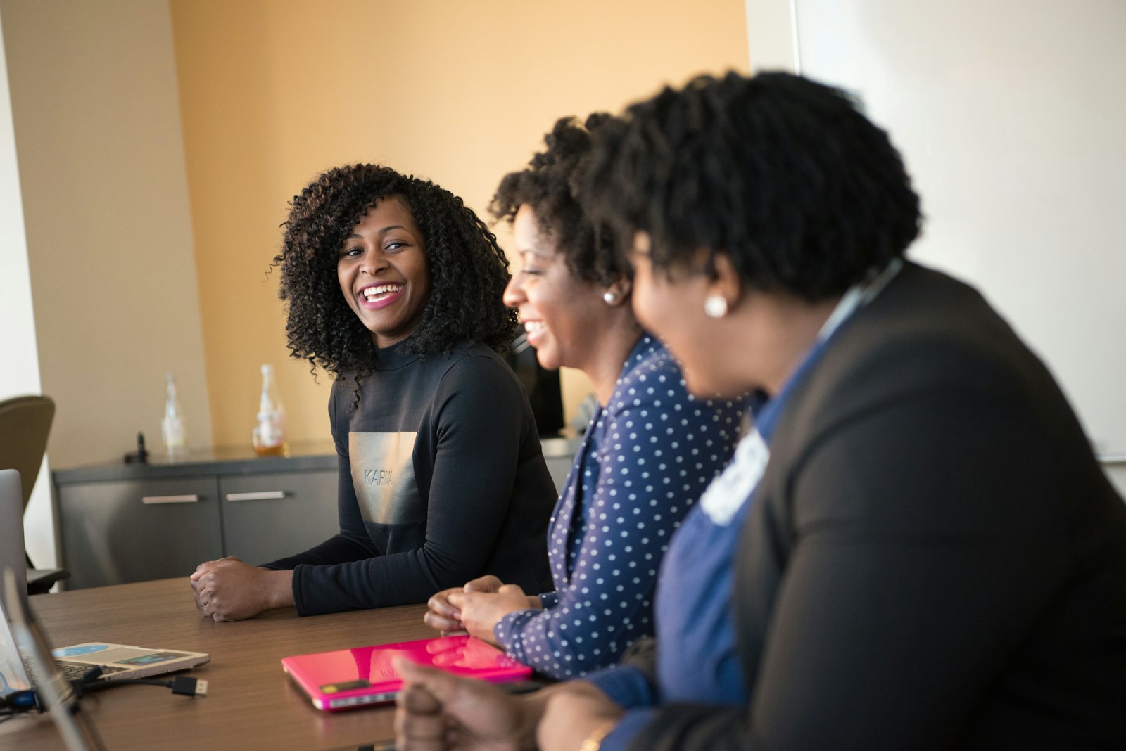 Three women smiling and talking at a table